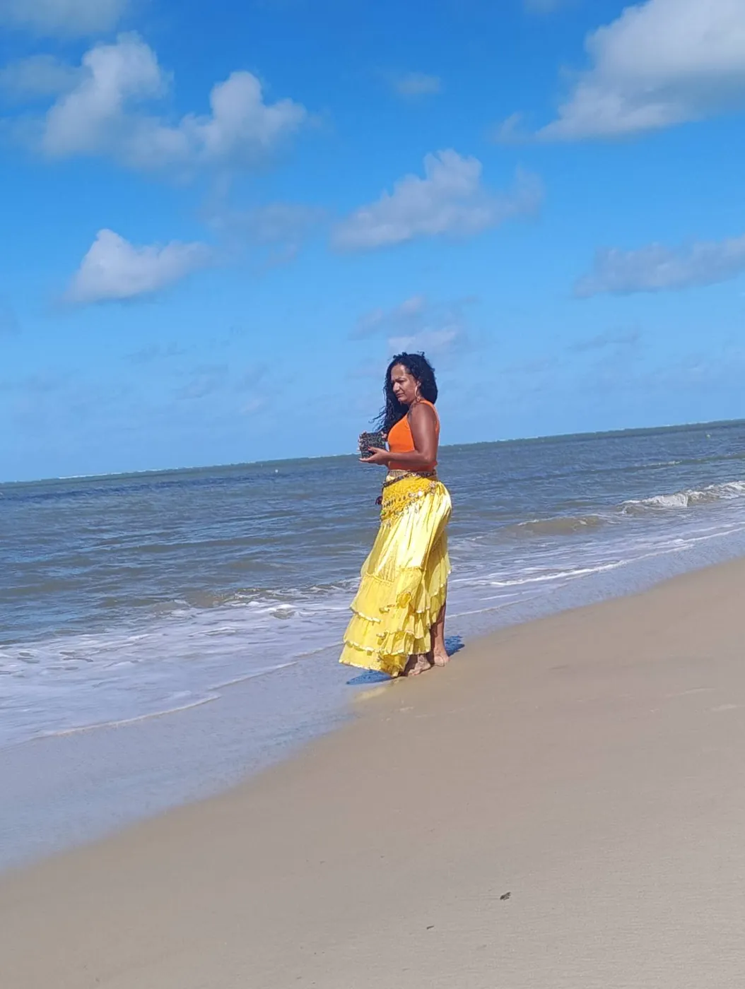 Liviã de saia amarela caminhando na beira do mar